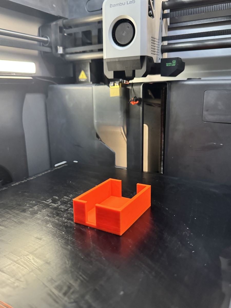 Orange 3D-printet holder på printerens byggeplade